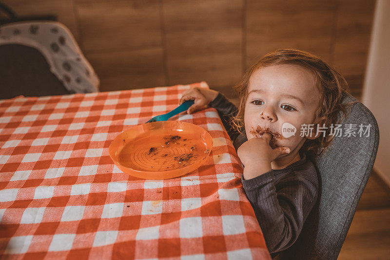 蹒跚学步的小男孩在吃面包和坚果酱