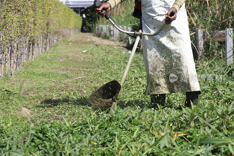 园丁正在用割草机把草割短。园丁用割草机清理后院。园丁使用设备修剪草坪。