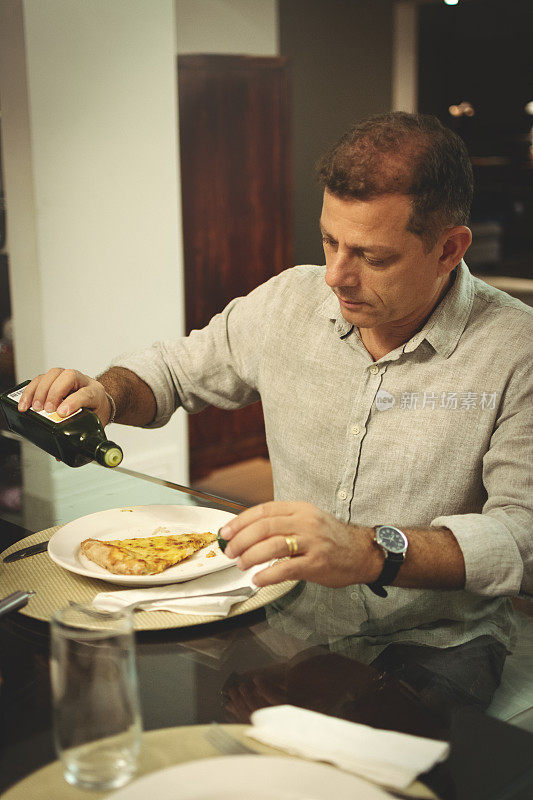 男人吃披萨，用橄榄油调味