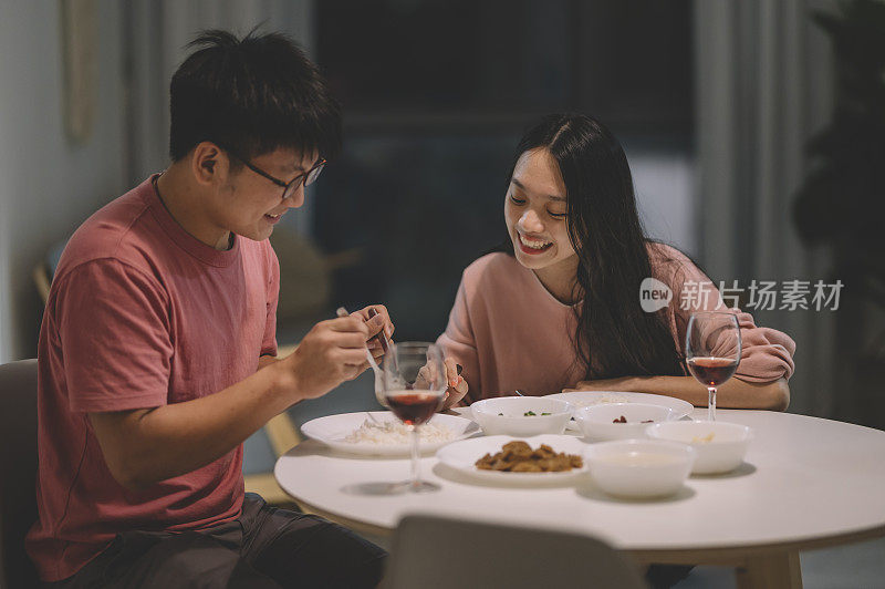 周末，一对亚洲华人夫妇在家里用红酒和中国菜共进晚餐