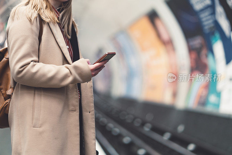 一个女人在用手机等地铁