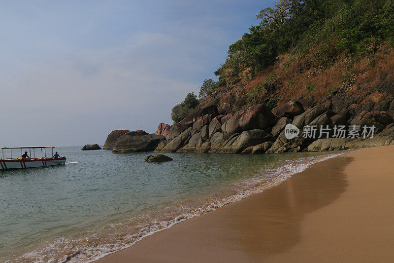 热带岛屿天堂的图像，蝴蝶海滩，Palolem，果阿，印度，棕榈树，私人附近的蜜月海滩与金色的沙子，温暖的绿松石海背景照片，岩石，悬崖面和游客度假