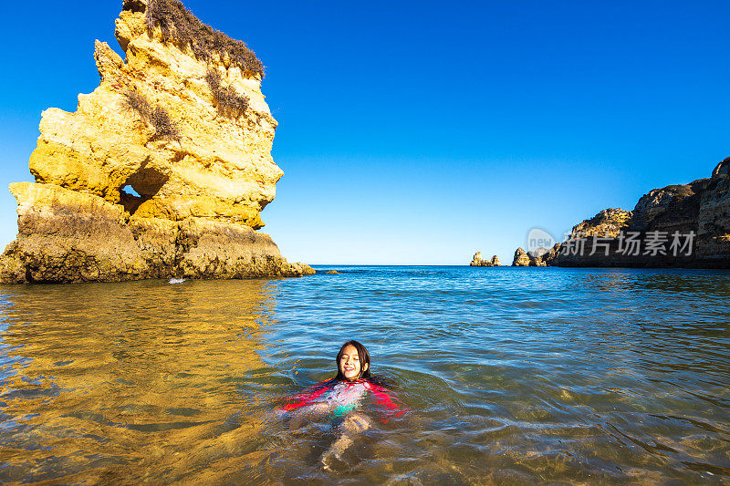 在葡萄牙阿尔加维普拉亚多纳阿纳海滩冰冷的绿松石水中游泳的女孩