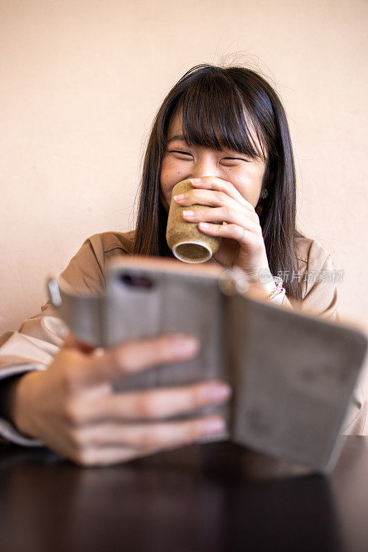 年轻女子使用智能手机，喝日本茶
