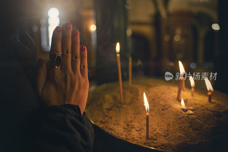 特写女人手在教堂祈祷，蜡烛在大教堂，希望的概念