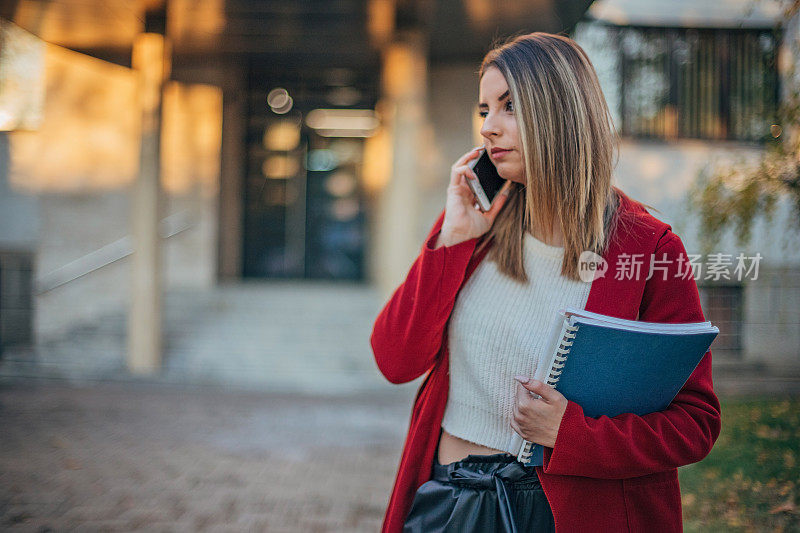 女学生拿着书在打电话