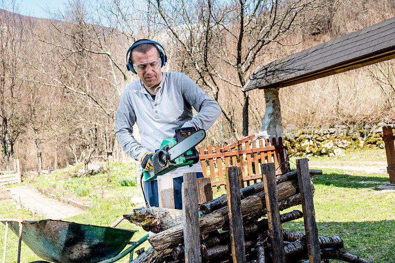 花园里的男人用电锯砍柴