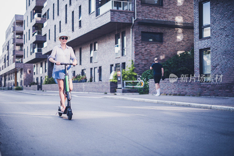 阳光明媚的日子里，快乐的女人骑着电动车。