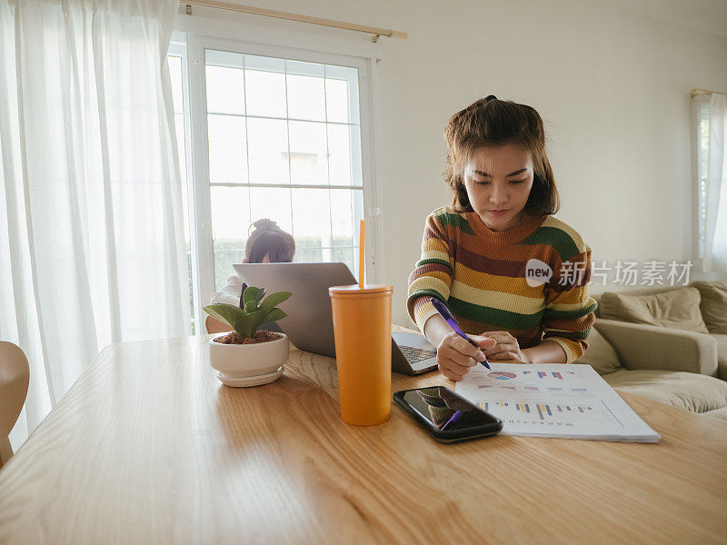 年轻的母亲在家里帮助小女孩做作业。