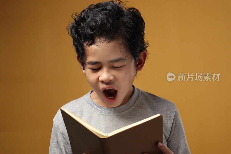肖像年轻的亚洲学生男孩疲倦困倦和打哈欠时读书，学生疲倦时努力学习