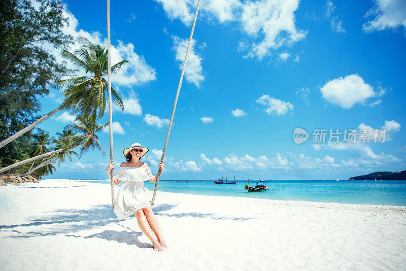 美丽的女人在热带海滩荡秋千，帕岸岛。泰国。