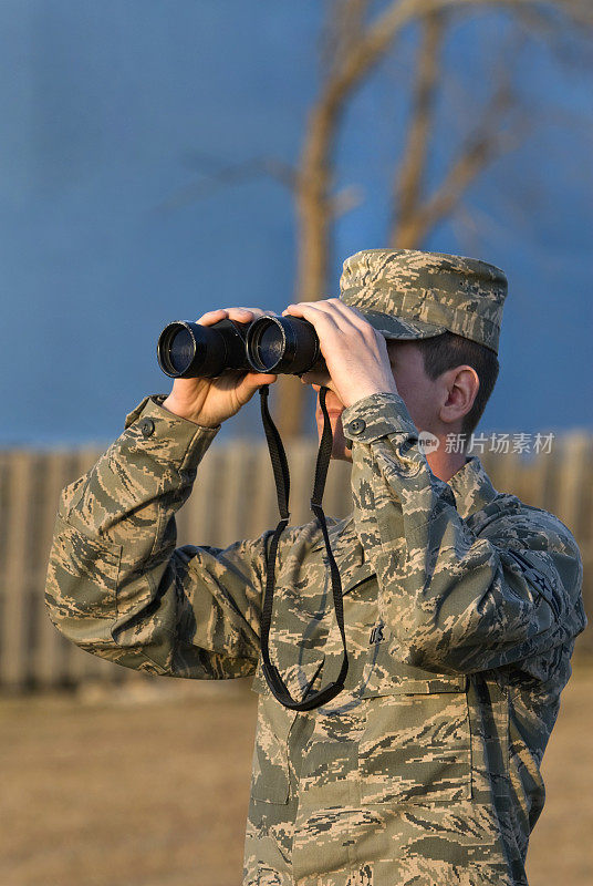 在日落时用双筒望远镜的士兵