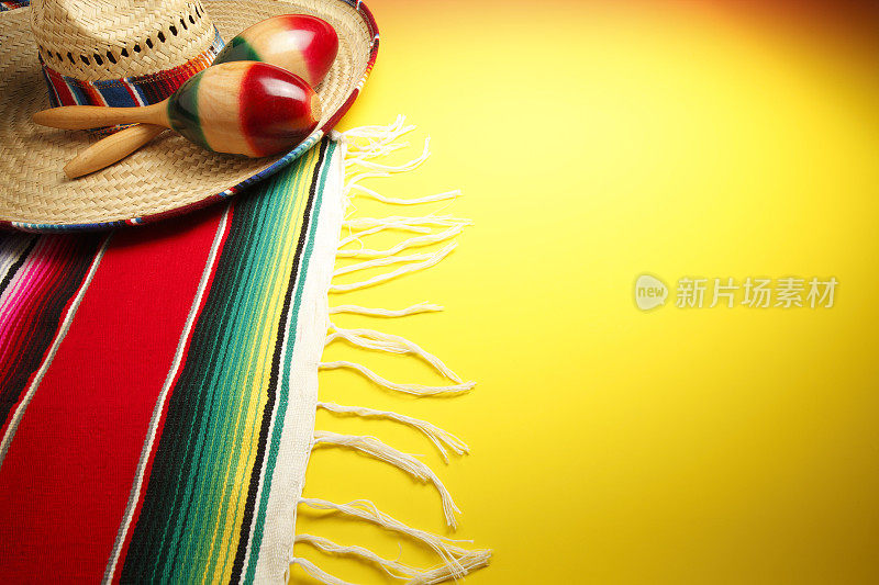 帽子上的沙球和黄色背景上的多色墨西哥毛毯