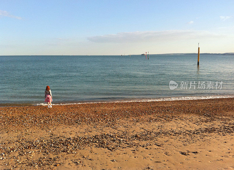 英国，朴茨茅斯海滩上的女孩把石头扔进海里