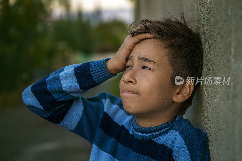 沮丧的小男孩的肖像倾斜的墙壁