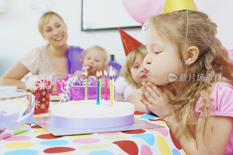 小女孩吹灭蛋糕上的蜡烛庆祝生日