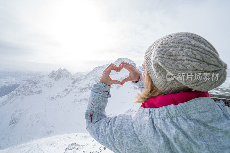 年轻女子在滑雪坡上做心形