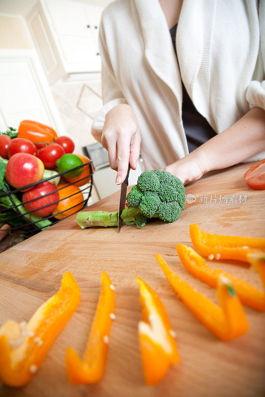 家庭主妇在切菜板上切花椰菜和其他蔬菜