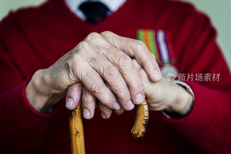 90岁老人双手拄着拐杖。