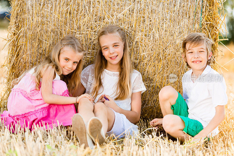 孩子们坐在一捆干草旁