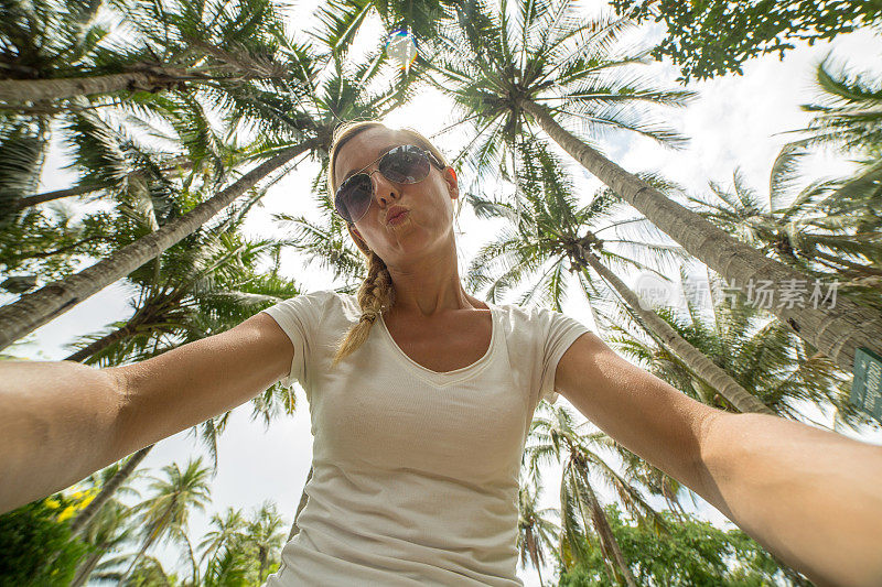 一名年轻女子在棕榈树下自拍