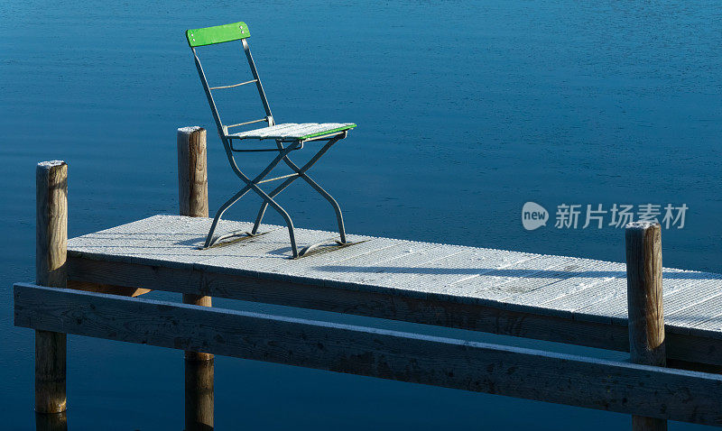 阳光下的折叠椅在结冰的码头上