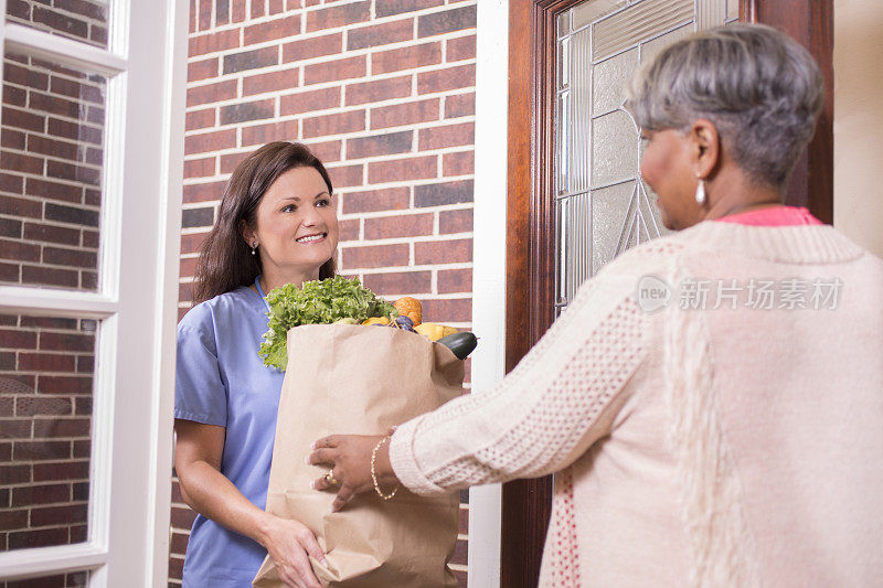 志愿服务:一名妇女在家中为老年妇女送杂货。