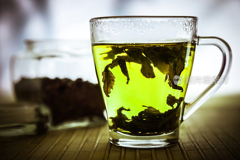 木桌上的玻璃茶杯里装着绿茶