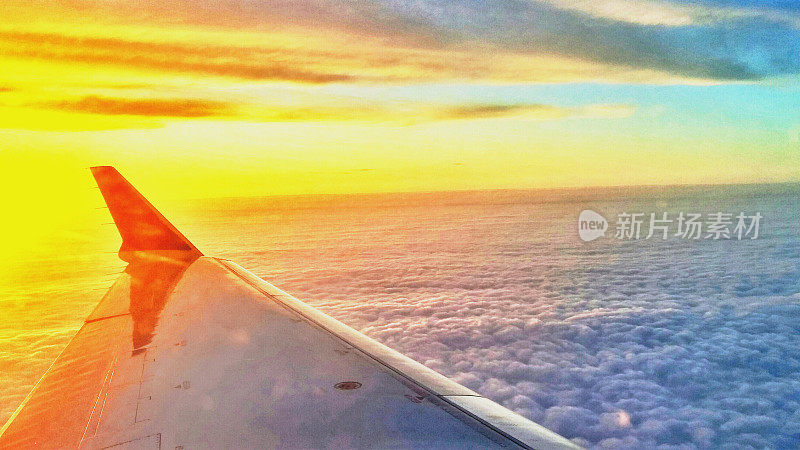 明亮的黄色辉映在飞机机翼上的夕阳天空