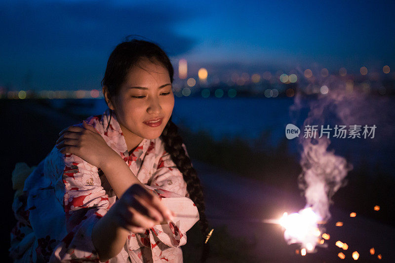 年轻的浴方女子玩火花附近的河