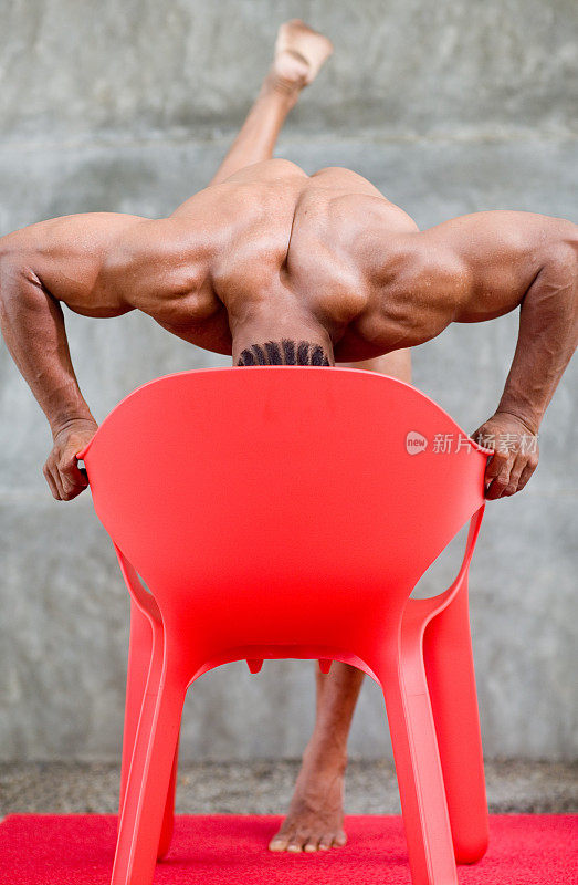 平衡的身体建设者在红色的椅子