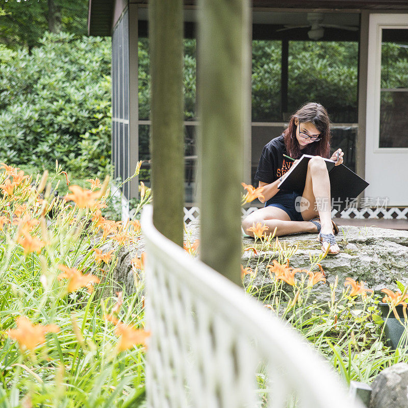 少女在速写本上画百合花