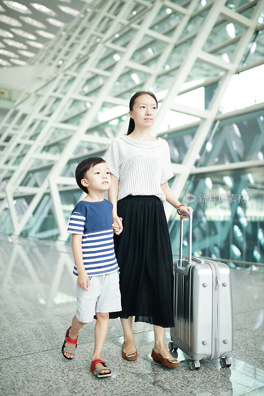 一个女人带着她的孩子经过机场航站楼