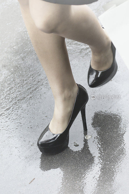 黑色高跟鞋在潮湿的路面上反射