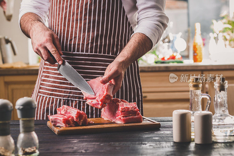 男人在家庭厨房的一块木板上切新鲜的肉