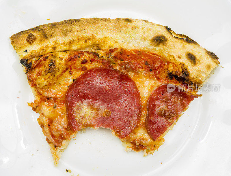 一个白色盘子上被咬的披萨的特写。