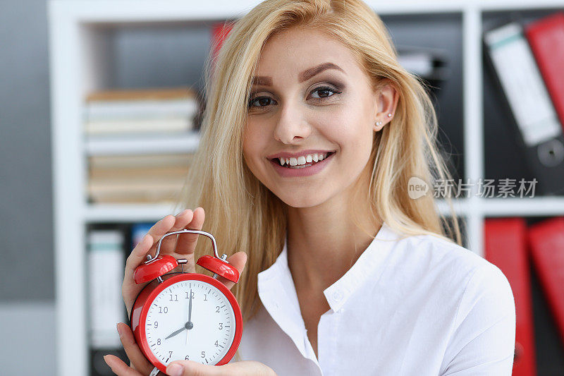 微笑的商业妇女手里拿着时钟