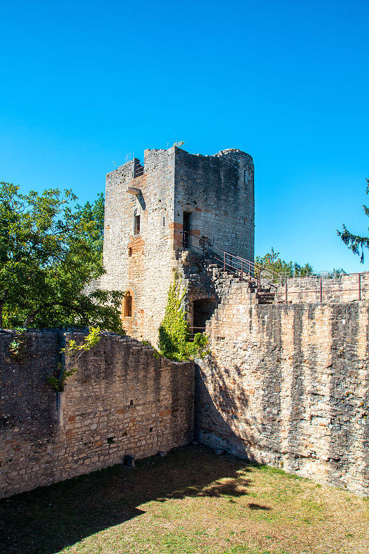 在阳光明媚的夏日里，古老的石头和岩石废墟墙和法国古城堡的方塔