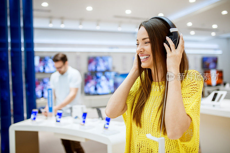 可爱迷人的快乐女孩在一个科技商店测试耳机的特写。