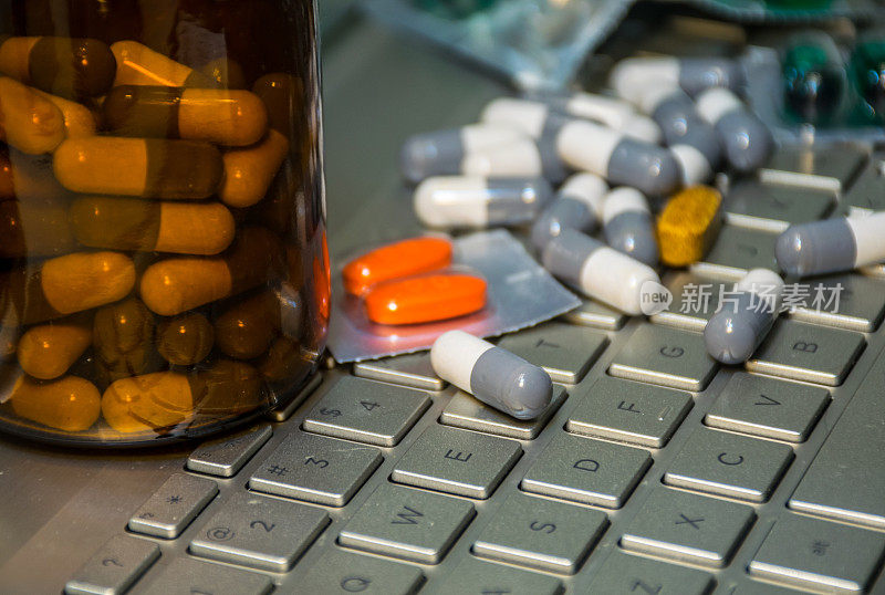 键盘笔记本电脑覆盖了药丸和止痛药和药瓶