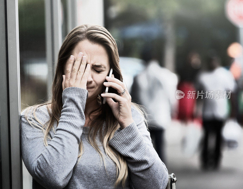 哭泣的女人在街上打电话，很痛苦