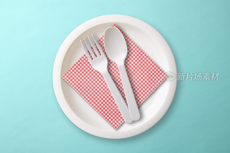 白色塑料盘子，在蓝色的背景上有民俗，勺子和餐巾