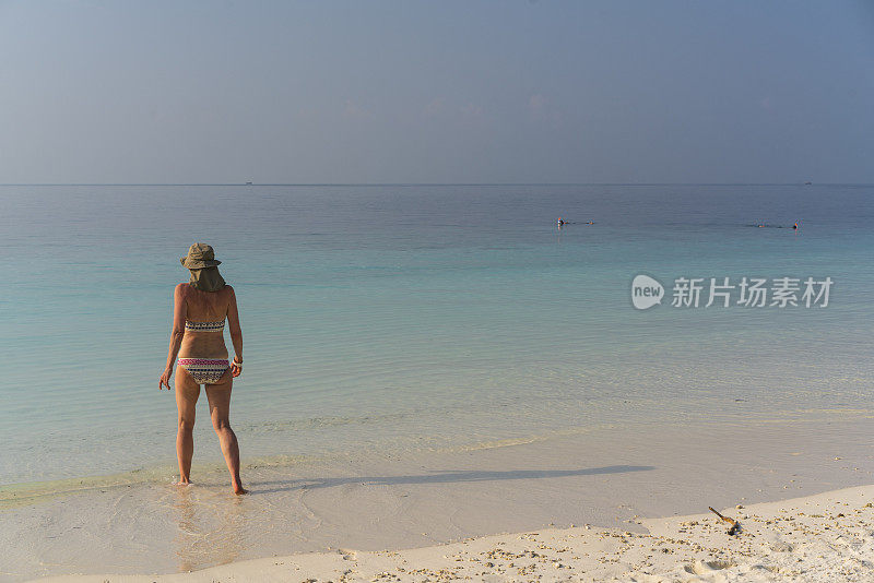 4月，马尔代夫，游客，老妇人带着相机进入离Maafushi岛不远的沙滩