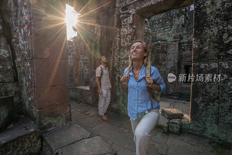 旅游夫妇一起探索古老的寺庙在日落，背包上准备发现亚洲;两人共享假期的理念;柬埔寨吴哥窟