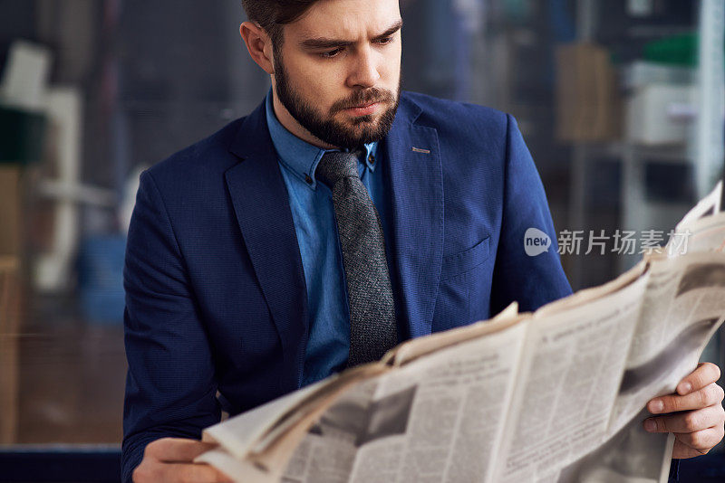 不高兴的男企业家皱着眉头，留着胡子，在机场专心致志地看报纸