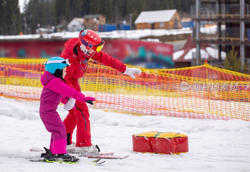这孩子跟着教练学滑雪。