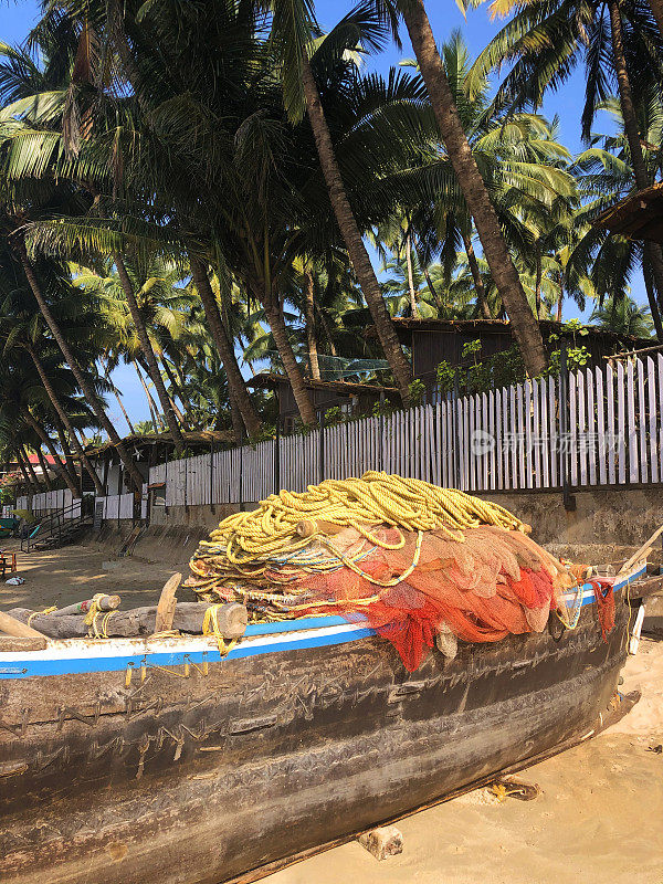 印度果阿海滩，木制渔船停泊在棕榈树旁的海滩上