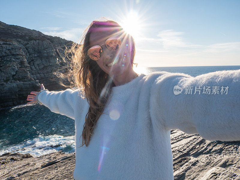 日落时分，一名女子在悬崖上自拍