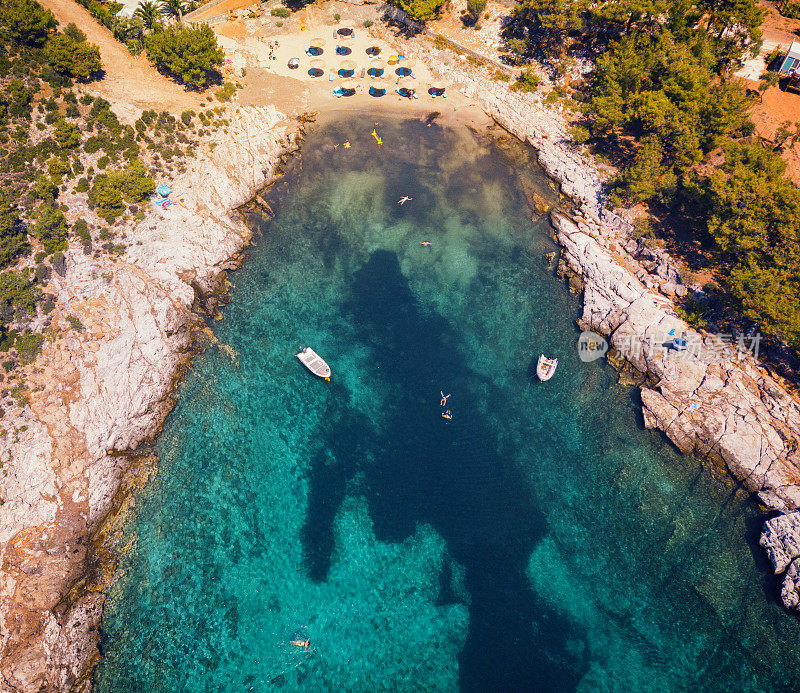 鸟瞰图美丽的小海滩上的希腊岛，岩石海岸与绿松石海