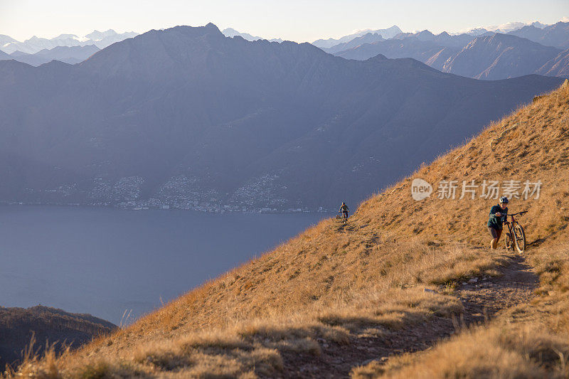 日出时分，朋友们推着山地车爬上长满青草的山脊